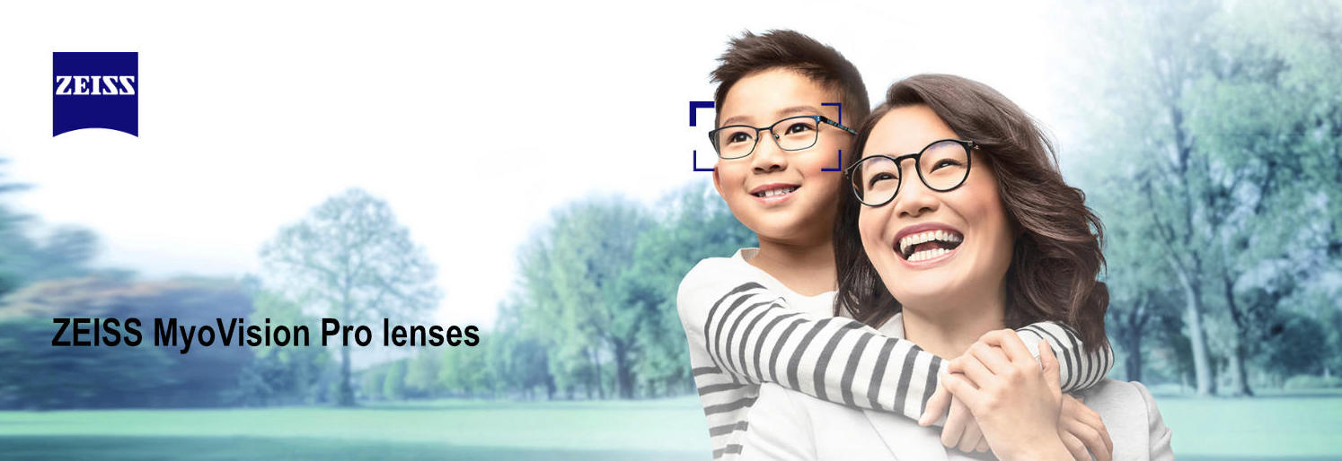 Young smiling Asian child being piggy backed by his mother gazing in the distance wearing glasses with the Zeiss MyoVisoin Pro lenses for the slowing of myopia progression